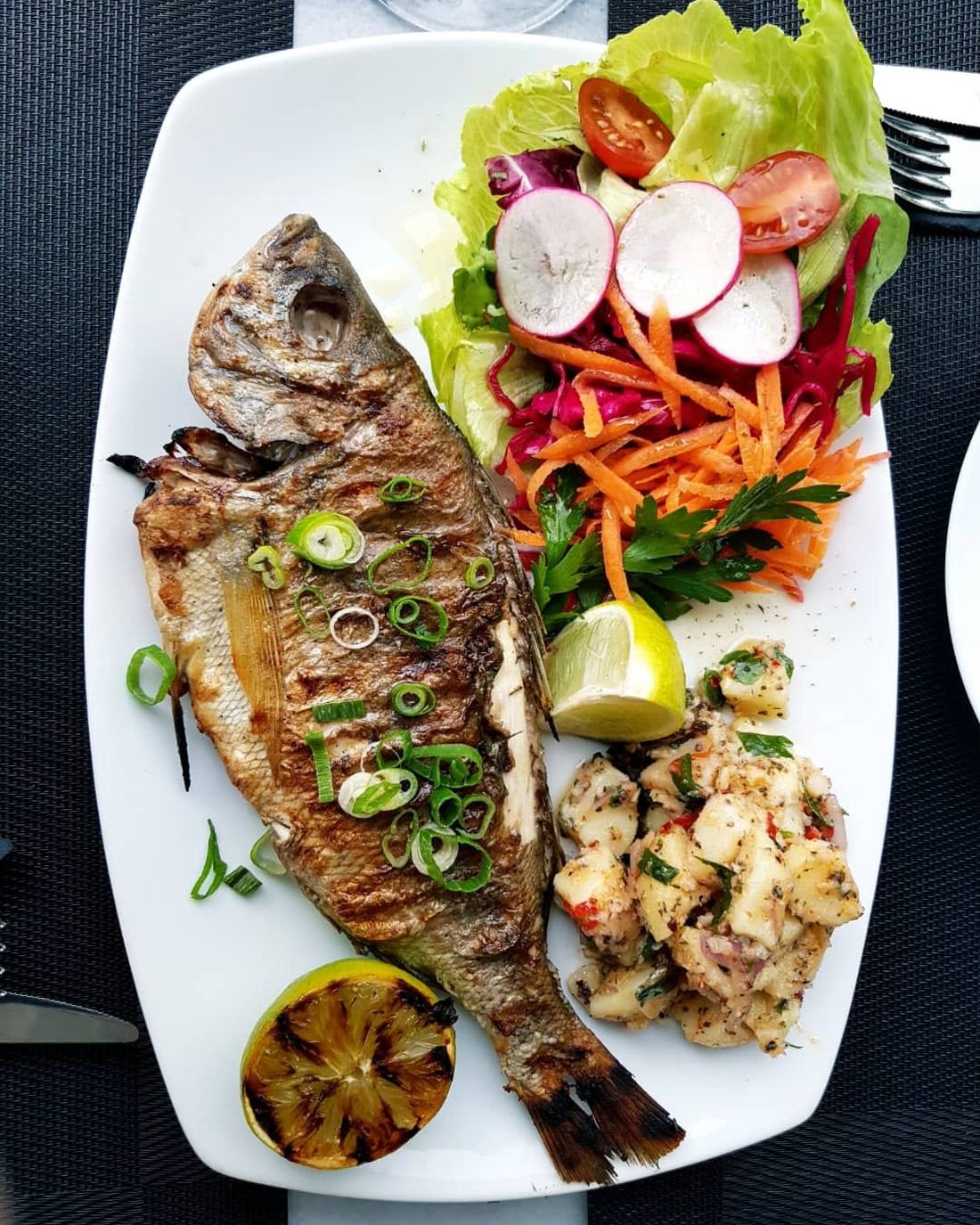 Whole grilled fish with charred lemon and leaves