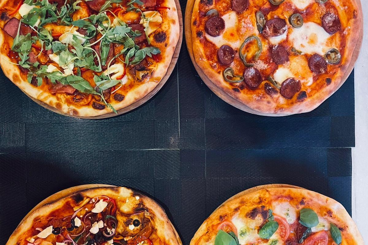 Four freshly made pizzas seen from above